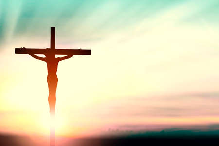 Silhouette of man with raised hands over blur cross concept for religion, worship, prayer and praise.の写真素材