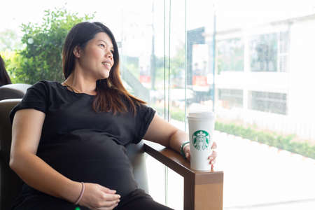 Hatyai ,Thailand-August 05 : Young beautiful woman pregnant with Starbucks Hot beverage coffee on hand on 05 August 2017 at Central Festival, Hatyai, Thailand.のeditorial素材