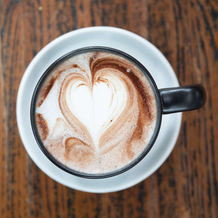 Closeup one coffee cup of hot black cappuccino on clean wooden table in morning light. space for text design. Aroma love caffeine smell.の写真素材