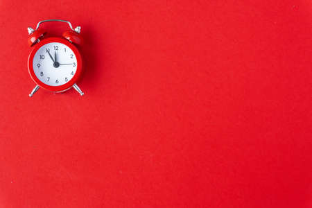 Creative flat lay vintage clock on red office table top view background concept alarm clock on red paper color with copy space in minimal style, empty template for text, break workplace at noon for lunch, back to school.の写真素材
