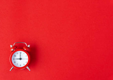 Creative flat lay vintage clock on red office table top view background concept alarm clock on red paper color with copy space in minimal style, empty template for text, break workplace at noon for lunch, back to school.の写真素材