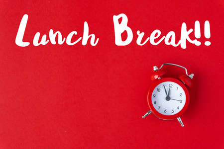 Creative flat lay vintage clock on red office table top view background concept alarm clock on red paper color with copy space in minimal style, empty template for text, break workplace at noon for lunch, back to school.の写真素材