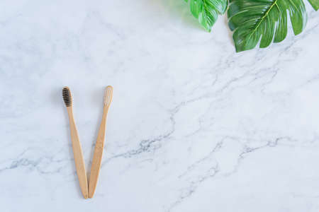 Bamboo wood toothbrush on clean white marble table top view background concept for save the earth day, world environmental, plastic free, kitchen flat lay lifestyle, bathroom reusable wood product.の写真素材