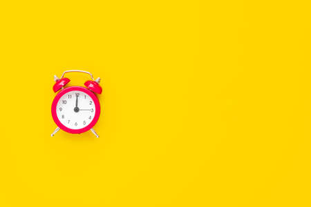 Abstract creative flat lay vintage yellow table top view office background concept red clock on paper color in minimal style, Hot summer holiday time to break workplace at noon for lunch, Retro Hipster back to school vacationの写真素材