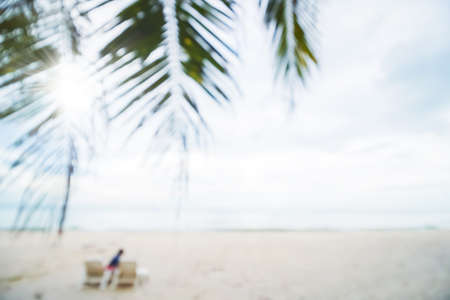 Abstract soft blur nature tropical beach with green coconut palm leaf and light wave bokeh background concept for blurry sky summer landscape water and sand, holiday ocean travel, relax vacation dayの写真素材