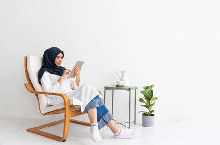 Young Muslim women Students is a creative freelance journalist sit writing to be entrepreneur job concept for hijab girl Islam religion Asian ethnic joyful internet banking on tablet mobile smartphoneの写真素材