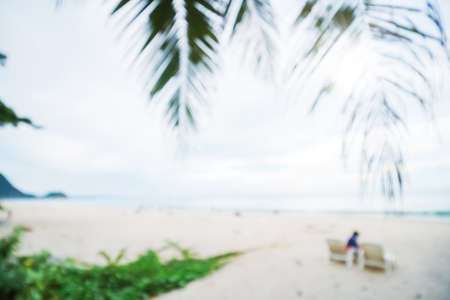 Abstract soft blur nature tropical beach with green coconut palm leaf and light wave bokeh background concept for blurry sky summer landscape water and sand, holiday ocean travel, relax vacation dayの写真素材