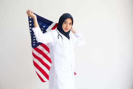 Young Muslim women exchange Students scholarship wear holding america flag over white background concept for hijab girl Islam religion Asian happy in united stage independent day cultureの写真素材