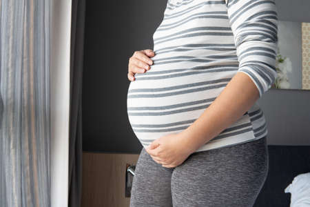 Young beautiful woman pregnant on bed at home concept - love, pregnancy, people and expectation over bedroom background.の写真素材
