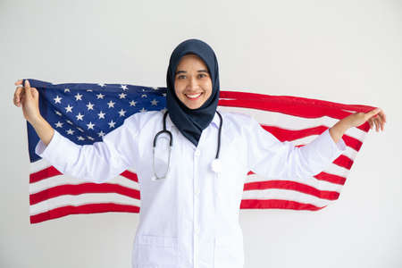 Young Muslim women exchange Students scholarship wear holding america flag over white background concept for hijab girl Islam religion Asian happy in united stage independent day cultureの写真素材
