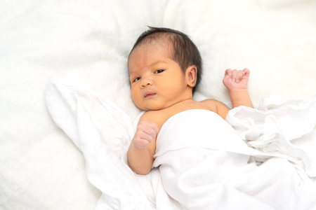 Cute newborn baby girl in white blanket onÂ nurseryÂ bed.Â AdorableÂ new born child, little...