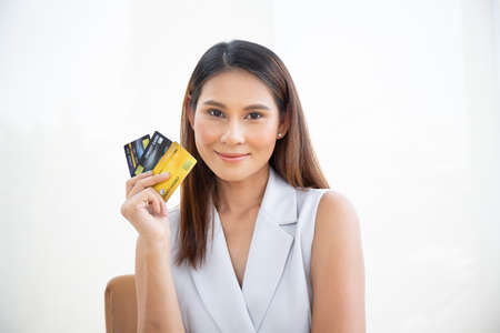 Happy asian woman smile at credit card, hold shopping reward bonus on isolate white background. Student customer people show debit reward for discount payment, travel loan salary dept purchase conceptの写真素材