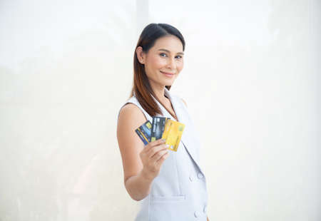 Happy asian woman smile at credit card, hold shopping reward bonus on isolate white background. Student customer people show debit reward for discount payment, travel loan salary dept purchase conceptの写真素材