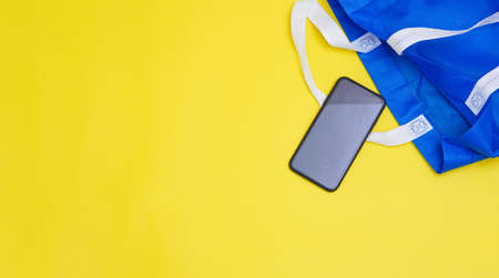 Flat lay eco blue shopping bag on paper yellow color background for tote present reduce mock up stuff shop. Linen canvas textile cloth sale on table top view, care world plastic free reusable concept.の写真素材