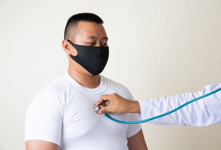 AsianÂ Man in medical maskÂ Coronavirus pandemic disease on grey background. COVID-19 virus