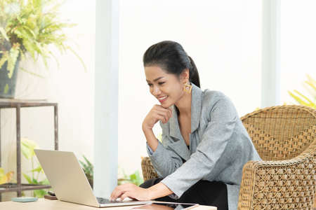 Young student woman use wireless internet learning and co-working at home on mobile tablet app. Modern girl people blogger couch on laptop education classroom online device, Social distancing in spaceの写真素材