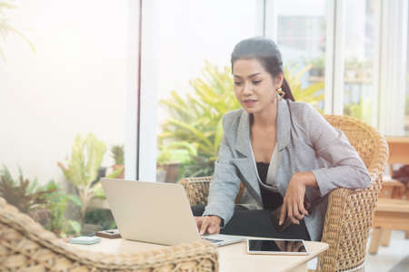 Young student woman use wireless internet learning and co-working at home on mobile tablet app. Modern girl people blogger couch on laptop education classroom online device, Social distancing in spaceの写真素材