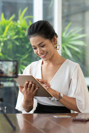 Young student woman use wireless internet learning and co-working at home on mobile tablet app. Modern girl people blogger couch on laptop education classroom online device, Social distancing in spaceの写真素材