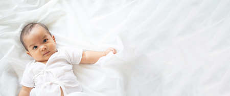 Cute newborn baby girl in white blanket onÂ nurseryÂ bed.Â AdorableÂ new born child, little boy eyes look people Family, new childhood, infant soft skin portrait concept.Â Jaundice syndromeÂ life hospital.の写真素材