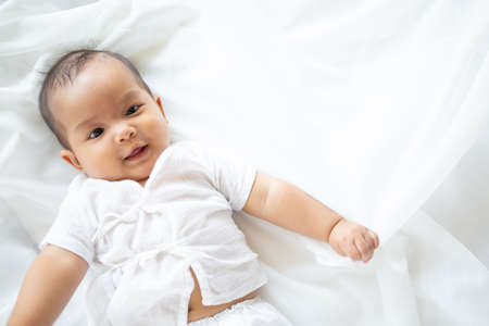 Cute newborn baby girl in white blanket onÂ nurseryÂ bed.Â AdorableÂ new born child, little boy eyes look people Family, new childhood, infant soft skin portrait concept.Â Jaundice syndromeÂ life hospital.の写真素材