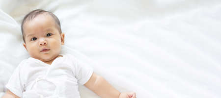 Cute newborn baby girl in white blanket onÂ nurseryÂ bed.Â AdorableÂ new born child, little boy eyes look people Family, new childhood, infant soft skin portrait concept.Â Jaundice syndromeÂ life hospital.の写真素材