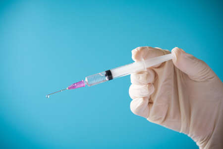 Doctor hand hold Syringe vaccine for corona virus on isolate blue background concept for Coronavirus pandemic disease, COVID-19 virus from epidemic outbreak to wide concept for social scientist vaccineの写真素材