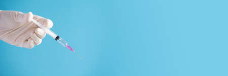 Doctor hand hold Syringe vaccine for corona virus on isolate blue background concept for Coronavirus pandemic disease, COVID-19 virus from epidemic outbreak to wide concept for social scientist vaccineの写真素材