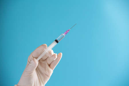 Doctor hand hold Syringe vaccine for corona virus on isolate blue background concept for Coronavirus pandemic disease, COVID-19 virus from epidemic outbreak to wide concept for social scientist vaccineの写真素材
