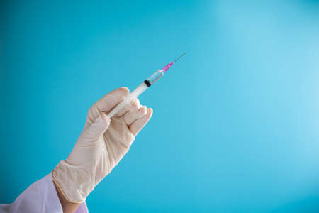 Doctor hand hold Syringe vaccine for corona virus on isolate blue background concept for Coronavirus pandemic disease, COVID-19 virus from epidemic outbreak to wide concept for social scientist vaccineの写真素材