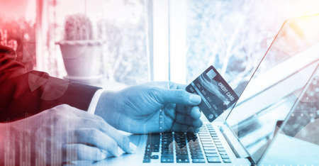 Business woman hand hold credit card to shopping internet online bill on computer, Debit saving purchase buy on table background. Shopaholic people retail pay sale money, bank terminal account conceptの写真素材