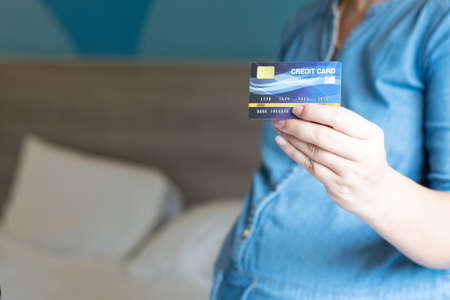 Business woman hand hold credit card to shopping internet online bill on computer, Debit saving purchase buy on table background. Shopaholic people retail pay sale money, bank terminal account conceptの写真素材