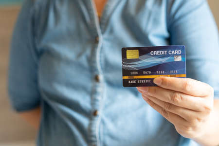Business woman hand hold credit card to shopping internet online bill on computer, Debit saving purchase buy on table background. Shopaholic people retail pay sale money, bank terminal account conceptの写真素材