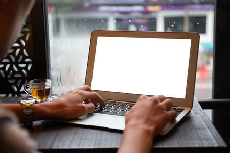 Young entrepreneur SME use notebook showing blank screen with clipping path display  in cafe concept.Â Hand of business man hold smartphone People use 5G cellular work app with modern internet of thingsの写真素材