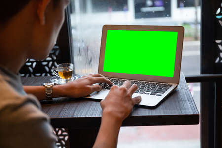 Young entrepreneur SME use notebook showing blank screen with clipping path display  in cafe concept.Â Hand of business man hold smartphone People use 5G cellular work app with modern internet of thingsの写真素材