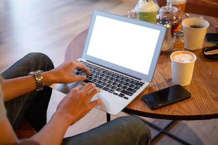 Young entrepreneur SME use notebook showing blank screen with clipping path display  in cafe concept.Â Hand of business man hold smartphone People use 5G cellular work app with modern internet of thingsの写真素材