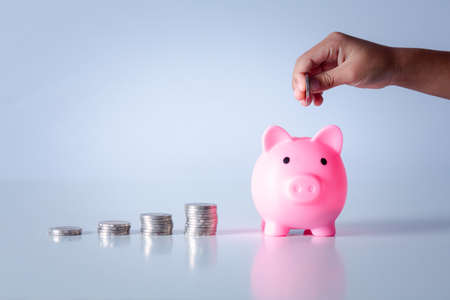 Hand of kid holding coin put in piggy bank with money stack growing growth saving money, Concept invesment for financial freedom plan, business deposit to hope successの写真素材