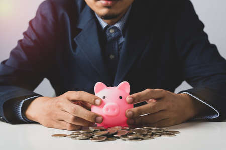 Hand of Business man holding coin put in piggy bank with money stack growing growth saving money, Concept invesment for financial freedom plan, business deposit to hope successの写真素材