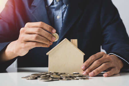 Hand of Business man holding coin put in piggy bank with money stack growing growth saving money, Concept invesment for financial freedom plan, business deposit to hope successの写真素材