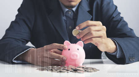 Hand of Business man holding coin put in piggy bank with money stack growing growth saving money, Concept invesment for financial freedom plan, business deposit to hope successの写真素材
