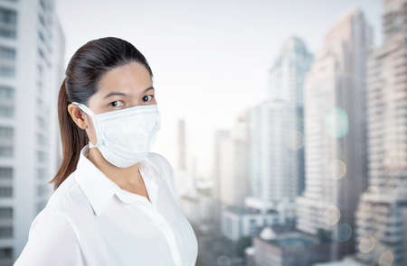 Young woman in safety medical mask in home isolation on blur outside office window view self business quarantine conceptの写真素材