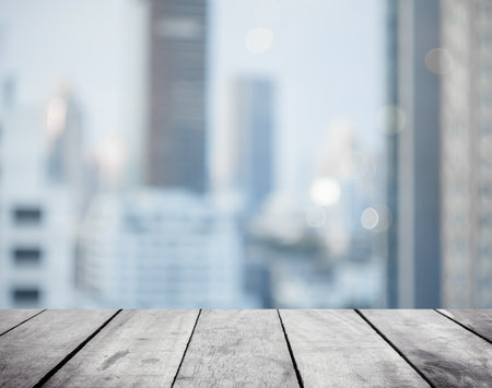 Panoramic empty grunge wood counter table top on blur glass window white light city bokeh background for product morning scene display montage, Abstract Blurry wide wooden desk in kitchen room rooftop.の写真素材