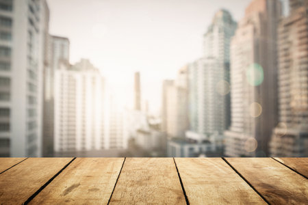 Panoramic empty grunge wood counter table top on blur glass window white light city bokeh background for product morning scene display montage, Abstract Blurry wide wooden desk in kitchen room rooftop.の写真素材