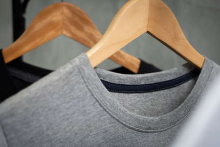 Young male in front blank black t-shirt Roll up sleeves template, Three color black white gray hang on cement background for your design mockup concept man tshirt product, woman shirt in fashion shop.の写真素材
