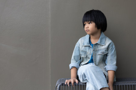 Girl child wearing blue jeans costume standing with her friend on in studio. A sad Girl looking away on grey wall background in family parents house Back to school 5 years old children Happy to learnの写真素材