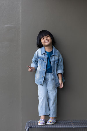 Girl child wearing blue jeans costume standing with her friend on in studio. A sad Girl looking away on grey wall background in family parents house Back to school 5 years old children Happy to learnの写真素材
