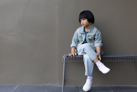 Girl child wearing blue jeans costume standing with her friend on in studio. A sad Girl looking away on grey wall background in family parents house Back to school 5 years old children Happy to learnの写真素材