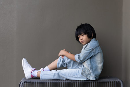 Girl child wearing blue jeans costume standing with her friend on in studio. A sad Girl looking away on grey wall background in family parents house Back to school 5 years old children Happy to learnの写真素材