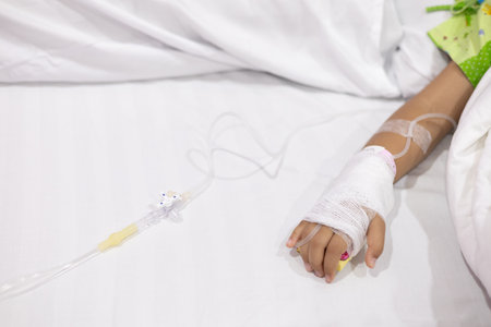 Child's hand fever patients have IV tube in hospital. Toddler girl wearing IV tube sleep in icu emergency bed room for leukemia coma from Cancer, Pediatric, Dengue fever. Sick children, infected.の写真素材