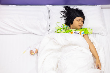 Child's hand fever patients have IV tube in hospital. Toddler girl wearing IV tube sleep in icu emergency bed room for leukemia coma from Cancer, Pediatric, Dengue fever. Sick children, infected.の写真素材