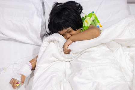 Child's hand fever patients have IV tube in hospital. Toddler girl wearing IV tube sleep in icu emergency bed room for leukemia coma from Cancer, Pediatric, Dengue fever. Sick children, infected.の写真素材